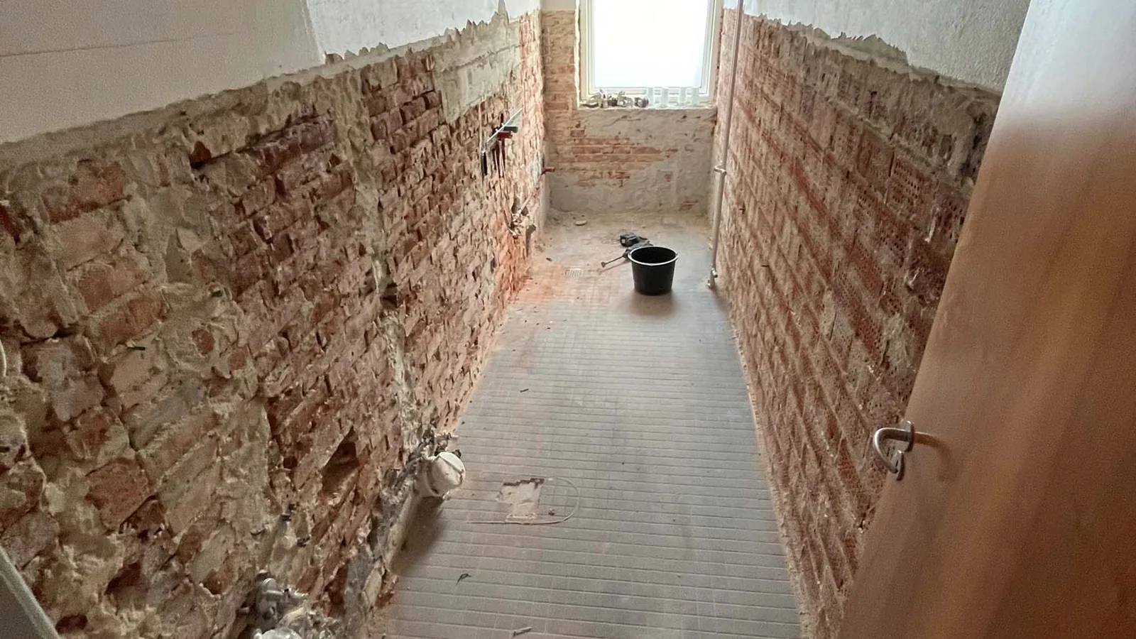 Gang afrenset til rå mursten midt i en totalrenovering